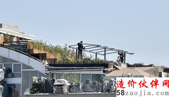 人济山庄B座楼顶被种中上了植物,有工人正在施工