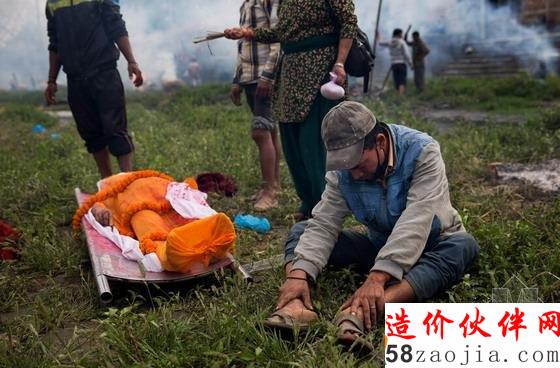 纪念仪式前,一名男子坐在遇难者身旁,低垂着头